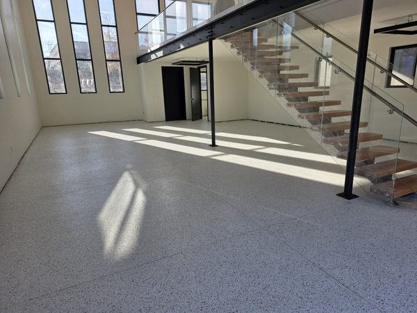Open commercial-style space with glass staircase and grey flake epoxy floor, after installation, Lake Norman NC